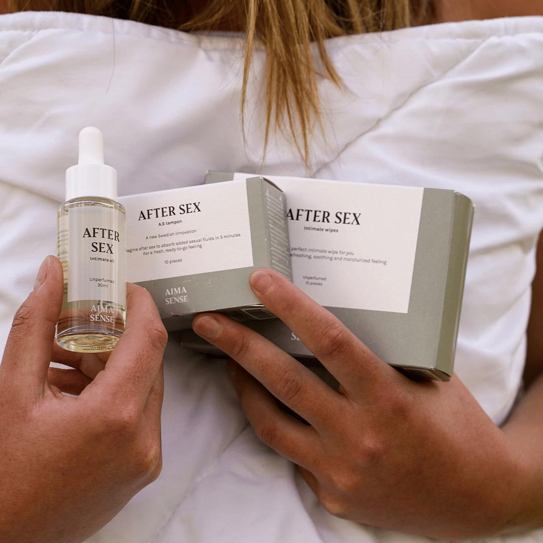 Kvinna håller Aima Sense After Sex olja, tamponger och wipes i handen